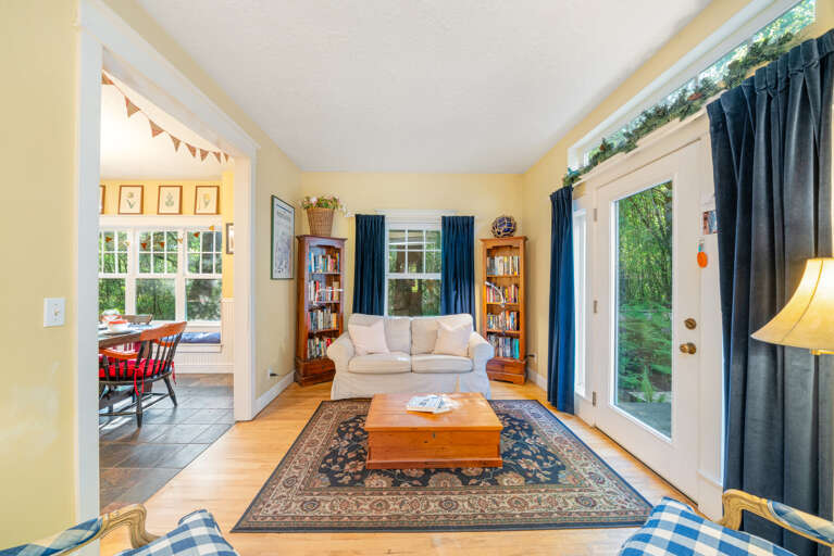 Sitting room with books and access to kitchen and outdoor space with hot tub and bbq
