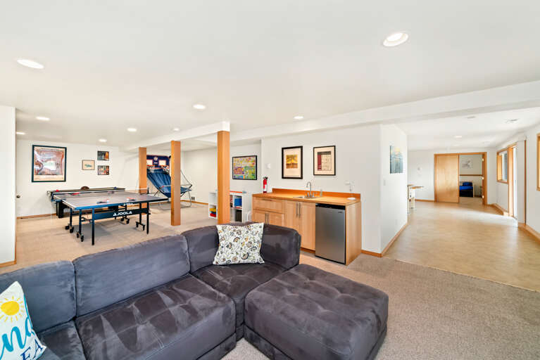 Downstairs game room with Ping pong table, Basketball game, Air Hockey, foos ball, and Large sectional couch, and mini fridge. 