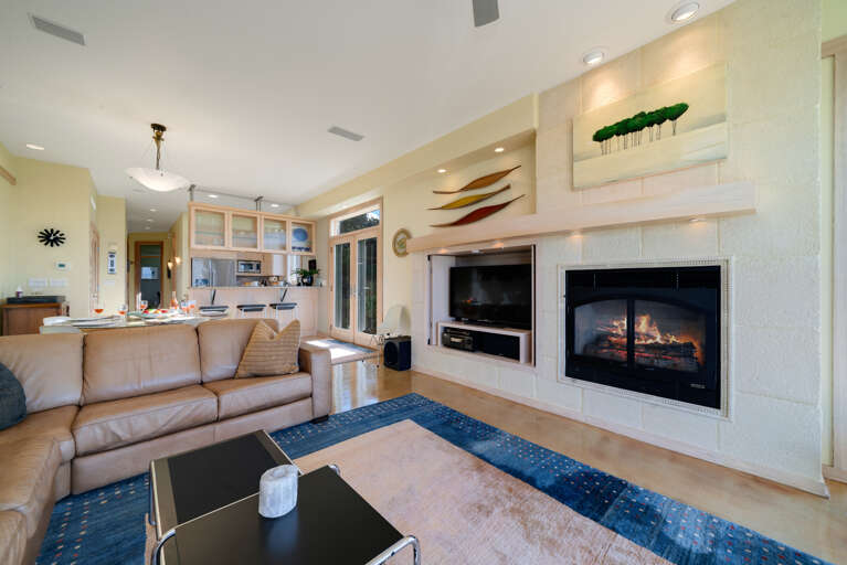 Living room with gas fireplace, Direct TV, Ocean views, Surround sound, Overhead fans, open to dining area.