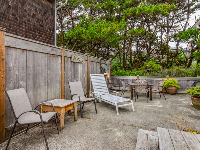 Fully fenced back yard with outdoor dining seating and lounge chairs 