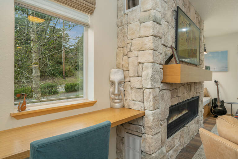 Living room with wrap around couch, gas fireplace, desk workspace. 