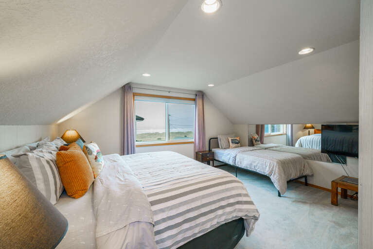 Upstairs master bedroom with King bed and Twin bed. Attached master bath with shower, access to third floor oceanview deck with fire table and deck chairs. 