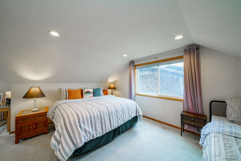 Upstairs master bedroom with King bed and Twin bed. Attached master bath with shower, access to third floor oceanview deck with fire table and deck chairs. 