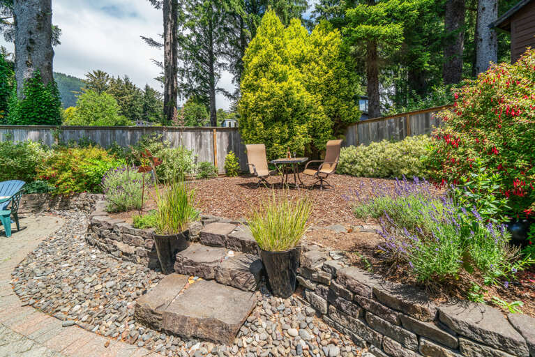 Back yard area with cocktail table, outdoor dining table with umbrella, Gas BBQ, and outdoor fire pit. 