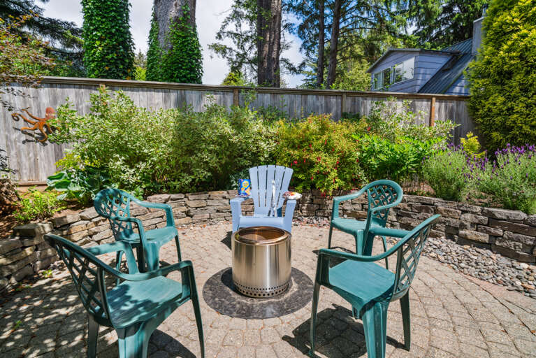 Back yard area with cocktail table, outdoor dining table with umbrella, Gas BBQ, and outdoor fire pit. 