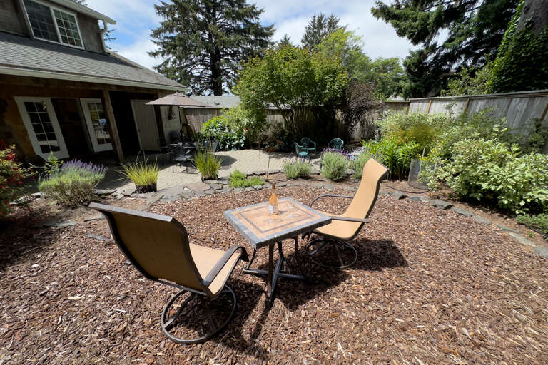 Back yard area with cocktail table, outdoor dining table with umbrella, Gas BBQ, and outdoor fire pit. 