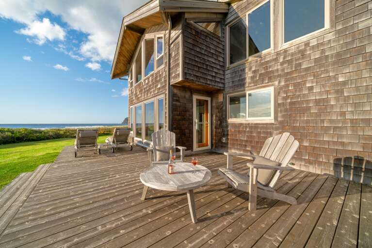 Ocean facing deck with outdoor dining and lounge chairs, large grass yard, direct access to the beach.
