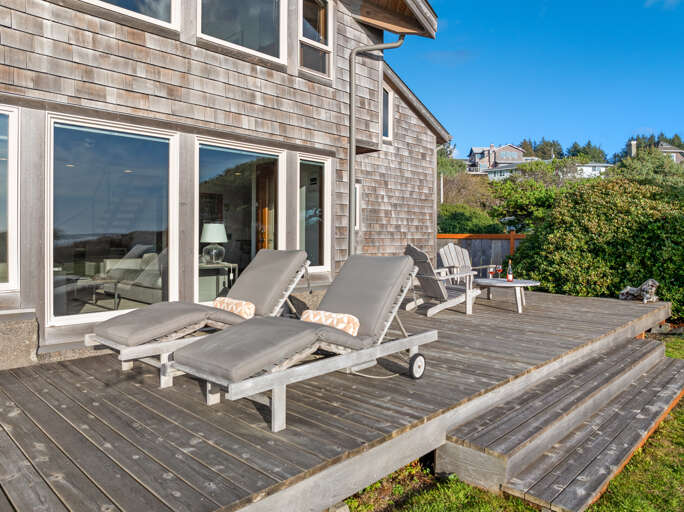 Ocean facing deck with outdoor dining and lounge chairs, large grass yard, direct access to the beach.