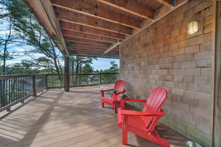 Lower deck with shaded area and Adirondack chairs.