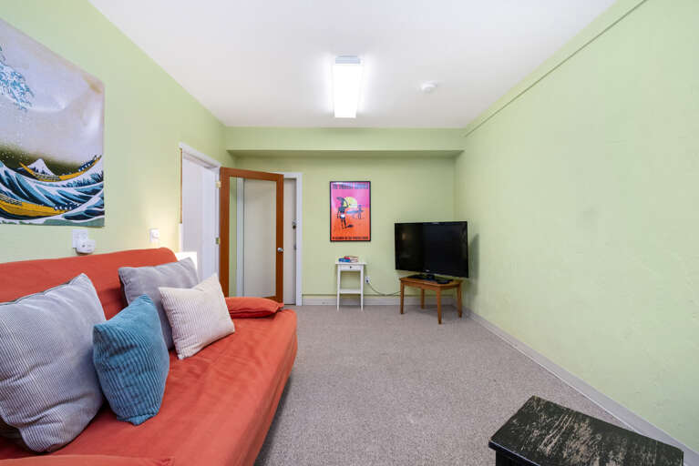 TV room off of the garage with Futon, card table, and Roku TV. 