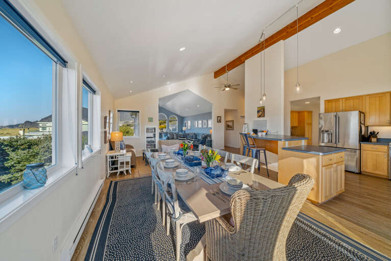 Dining table open to kitchen with breakfast bar and access to deck with ocean view