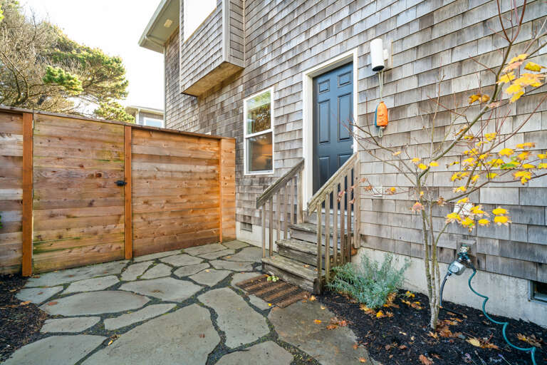 Fully fenced back yard has an outdoor shower, firepit and access to both the front yard and the back garage access. 