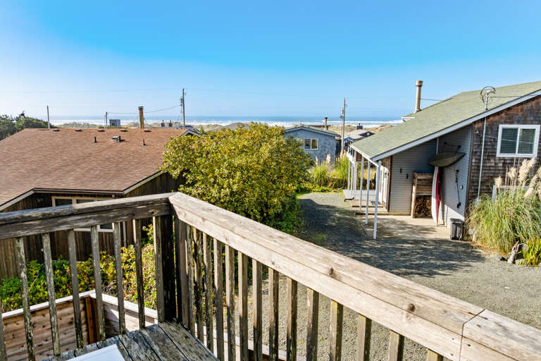 Deck off the living area with ocean views, outdoor dining table, and adirondack chairs. Wraps around to a wind blocked area as well. 