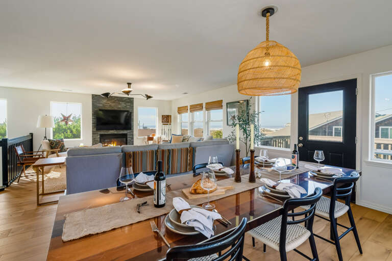 Large dining table open to Living area with streaming TV, ocean view, access to the deck with outdoor dining table.