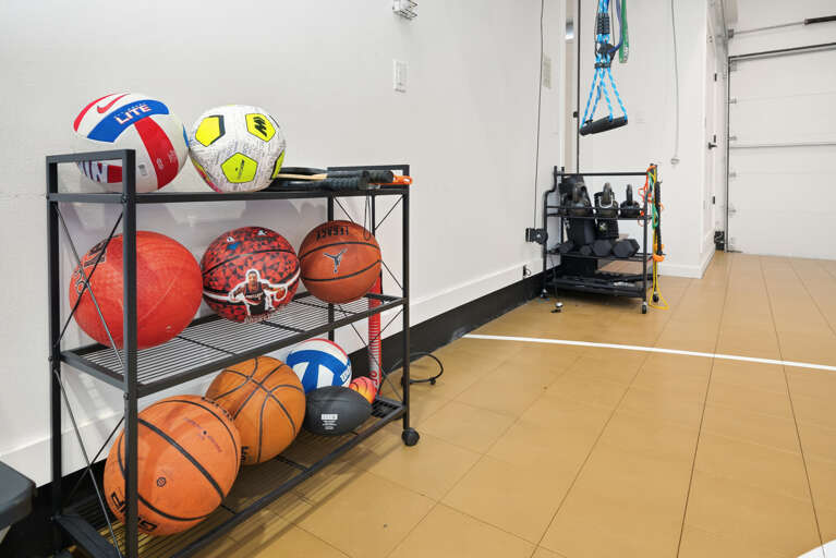 Sport court, free weights, and exercise mats in garage with window wall that opens up to outside. 