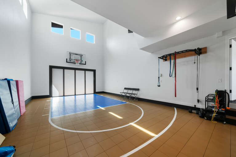 Indoor sports court with basketball hoop, pickleball, exercise corner and exercise mats