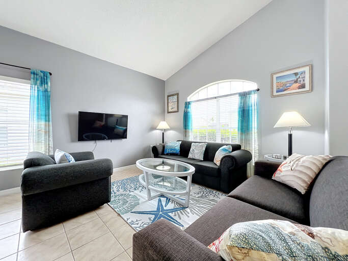 - Relax in a light filled living room with cozy seating and nautical themed decor
- Large windows and vibrant blue curtains create a fresh, coastal vibe throughout
- Watch your favorite shows on the wall mounted smart TV in this welcoming lounge space - Relax in a light filled living room with cozy seating and nautical themed decor
- Large windows and vibrant blue curtains create a fresh, coastal vibe throughout
- Watch your favorite shows on the wall mounted smart TV in this welcoming lounge space
