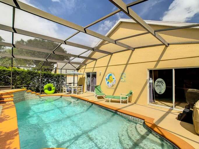 Pool area with a screened enclosure. There is a pool, lounge chairs, and a small dining set. Pool area with a screened enclosure. There is a pool, lounge chairs, and a small dining set.