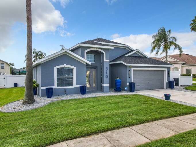 Modern coastal style home with bold navy exterior, arched windows, sleek doors, and tropical palm lined curb appeal. Modern coastal style home with bold navy exterior, arched windows, sleek doors, and tropical palm lined curb appeal.