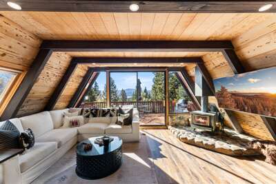 Relax in the bright, sun-filled living room! Setup with a wood burning fireplace, access to the hot tub on the deck and a 65" Smart TV.