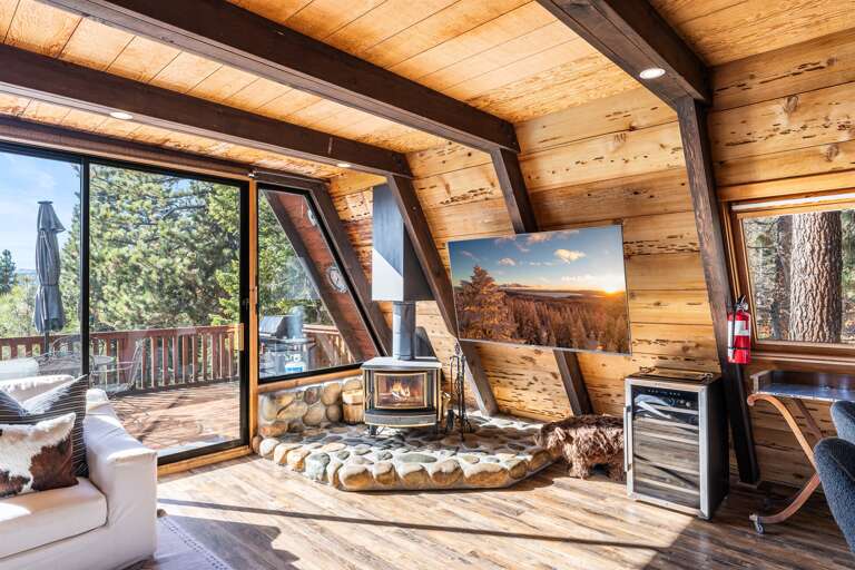 Relax in the bright, sun-filled living room! Setup with a wood burning fireplace, access to the hot tub on the deck and a 65" Smart TV.