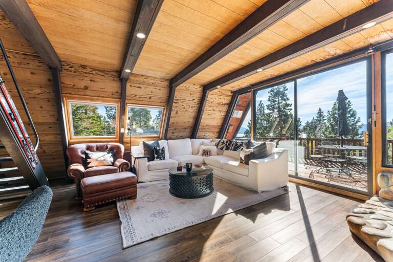Relax in the bright, sun-filled living room! Setup with a wood burning fireplace, access to the hot tub on the deck and a 65" Smart TV.