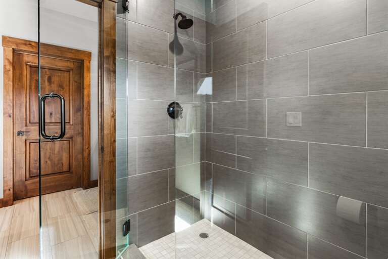 This bathroom features dual vanities and a spacious walk-in shower, providing both style and functionality. Thoughtfully stocked with shampoo, conditioner, and body wash for a comfortable stay.