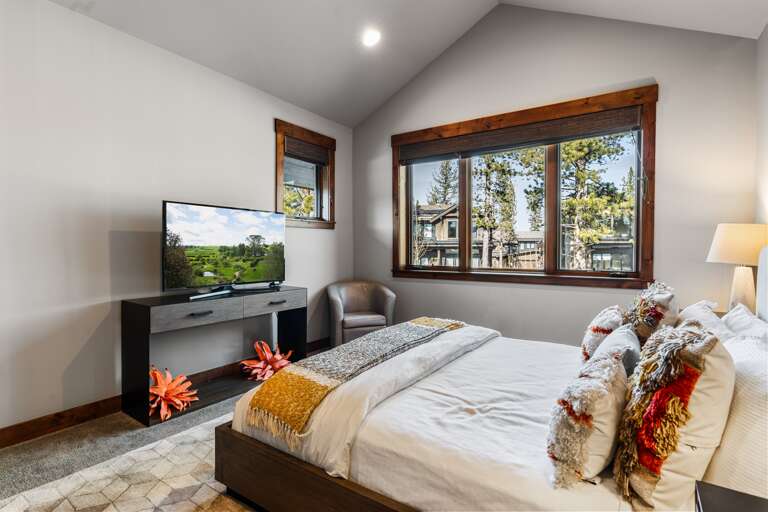 This luxurious upstairs master suite features a plush king bed, a 49" Smart TV, and an en-suite bathroom, offering a serene retreat perfect for unwinding after a day of Tahoe adventures.