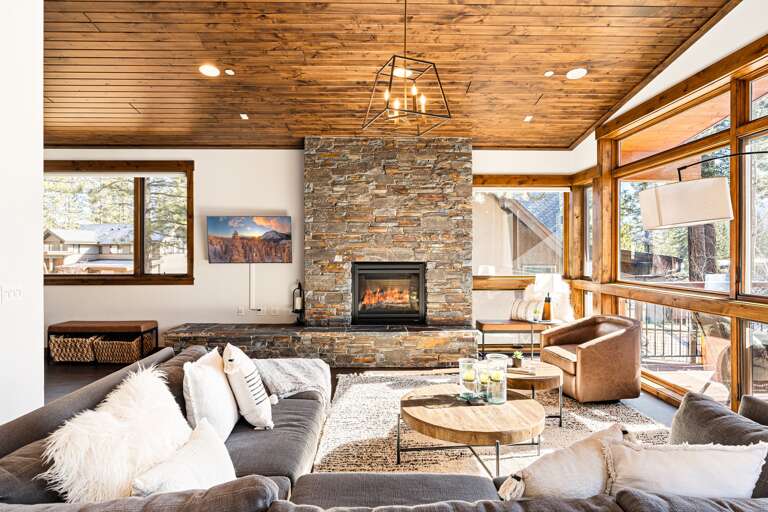 Relax in the inviting great room, where soaring ceilings and large windows flood the space with natural light while framing the picturesque mountain scenery. Cozy up by the stone fireplace and enjoy the 50" Smart TV. Relax in the inviting great room, where soaring ceilings and large windows flood the space with natural light while framing the picturesque mountain scenery. Cozy up by the stone fireplace and enjoy the 50" Smart TV.