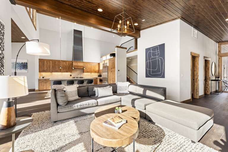 Relax in the inviting great room, where soaring ceilings and large windows flood the space with natural light while framing the picturesque mountain scenery. Cozy up by the stone fireplace and enjoy the 50" Smart TV. Relax in the inviting great room, where soaring ceilings and large windows flood the space with natural light while framing the picturesque mountain scenery. Cozy up by the stone fireplace and enjoy the 50" Smart TV.