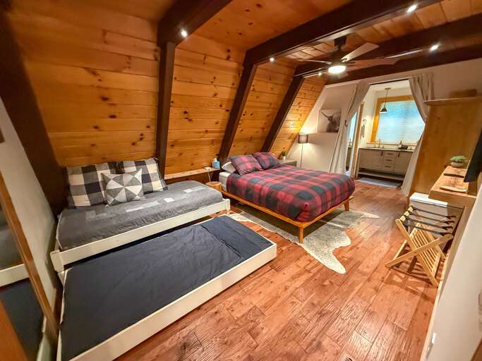 Rest easy in the spacious primary bedroom with a king bed, twin bed with trundle, a 55" Smart TV, and an en-suite bathroom featuring a walk-in shower and dual vanities for your convenience.