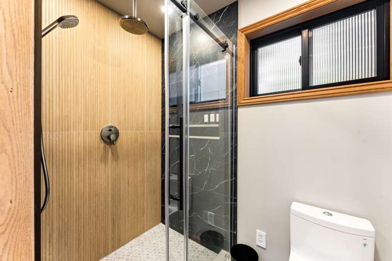 Rest easy in the spacious primary bedroom with a king bed, twin bed with trundle, a 55" Smart TV, and an en-suite bathroom featuring a walk-in shower and dual vanities for your convenience.