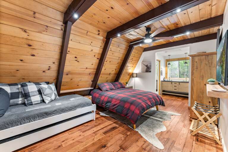 Rest easy in the spacious primary bedroom with a king bed, twin bed with trundle, a 55" Smart TV, and an en-suite bathroom featuring a walk-in shower and dual vanities for your convenience.