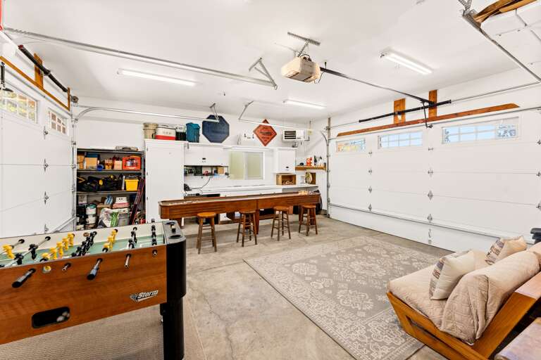The garage has been transformed into a fun-filled game room featuring shuffleboard, air hockey, and foosball — and it's fully heated for year-round enjoyment. In the summer, open up the garage door for fresh air and indoor-outdoor vibes!