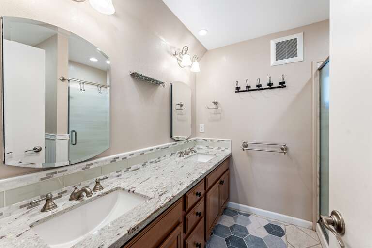 Full bath with walk-in shower and dual vanities.​