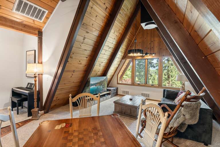 Relax and recharge in the upstairs living room featuring a 55" Smart TV, a cozy card table for game night, direct access to the upper patio, and a sofa bed for additional sleeping space.