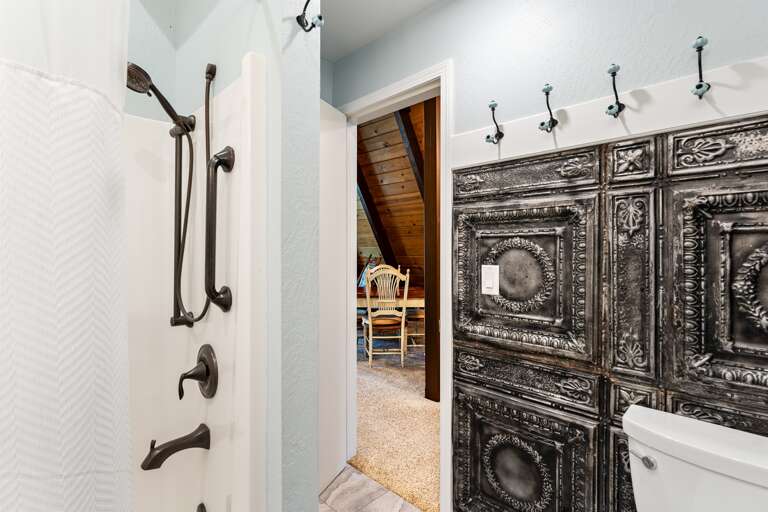 The upstairs bedroom features a queen bed, a ceiling fan, and access to the upper deck with fresh mountain views. It also connects to the Jack and Jill bathroom for added convenience.