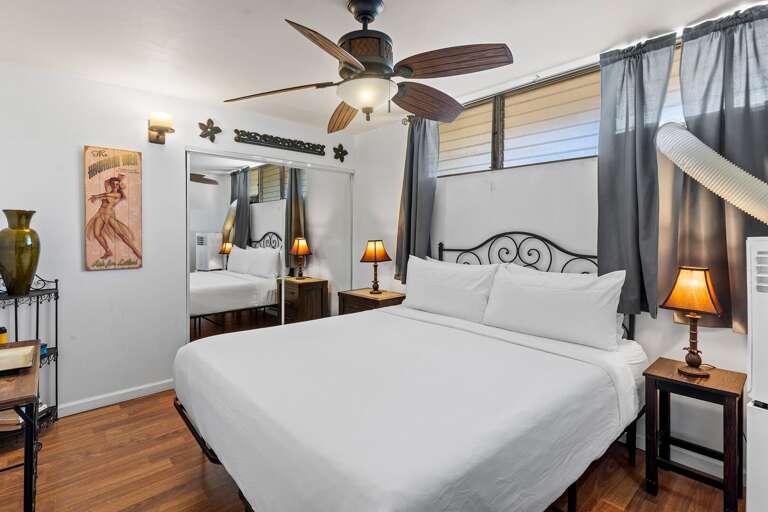 Bedroom With White Bedding, Wood Floors, Ceiling Fan, And Twin Table Lamps