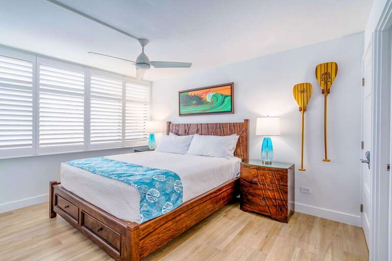 Bright Bedroom With Large Bed, Wooden Furniture, And Ceiling Fan