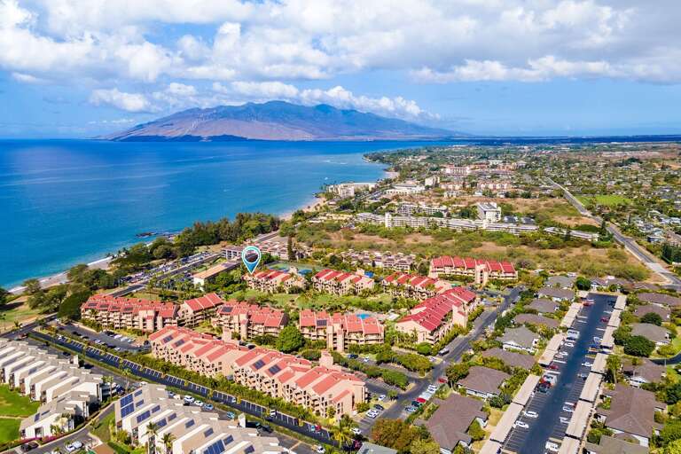 Aerial View Of Beachside Buildings Beneath Blue Skies By Mountain