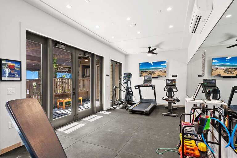 Spacious Fitness Facility Featuring Treadmill, Elliptical, And Exercise Bikes Beside Sliding Glass Doors Spacious Fitness Facility Featuring Treadmill, Elliptical, And Exercise Bikes Beside Sliding Glass Doors