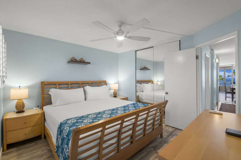 Bright Blue Bedroom With Wooden Bed And Breezy Balcony Access