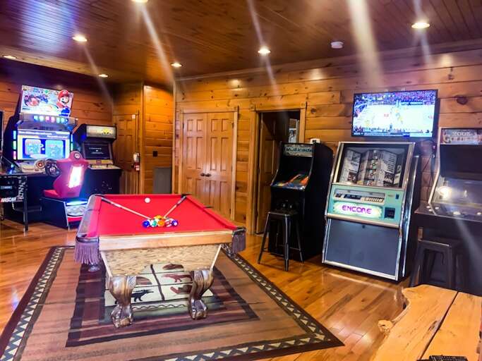 Wood-paneled Room With Red Pool Table, Arcade Games, And Television