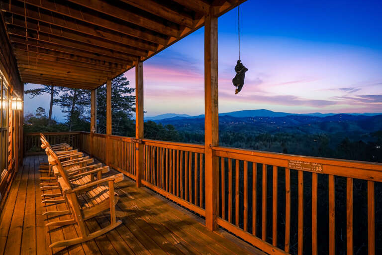 Wooden Deck With Rocking Chairs, Overlooking Serene Sunset And Mountains