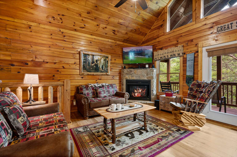 Wood-lined Living Space With Plush Seating, Patterned Rug, And A Blazing Fireplace
