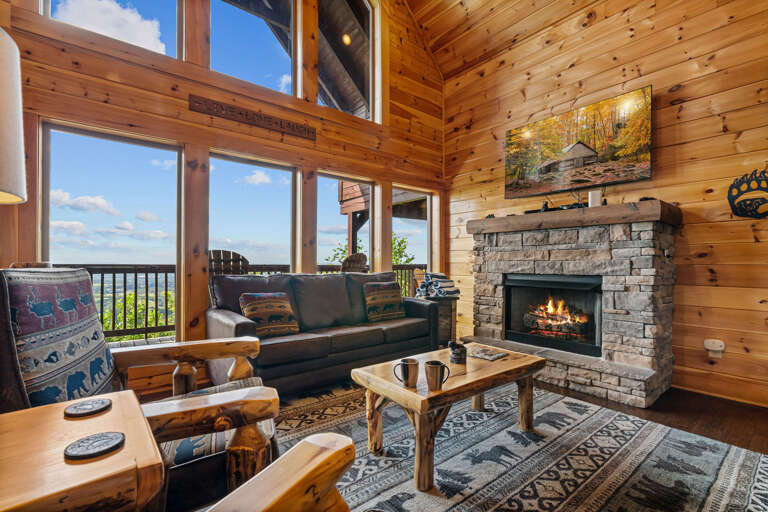 Rustic Room With Roaring Fireplace, Rugged Furnishings Overlooking Lush Landscape