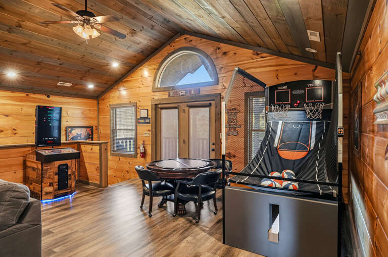 Wood-paneled Room With Arcade Game, Basketball Hoop, Round Table