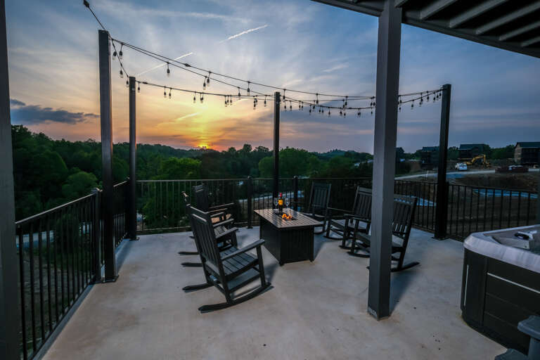 Sunset Scene With String Lights, Rocking Chairs, And Table On Terrace