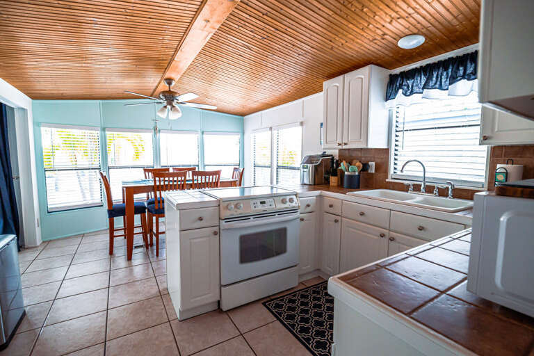 Bright, Breezy Vacation Rental Kitchen With White Appliances And Wooded Ceiling