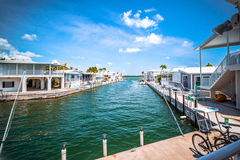Waterfront Walkway With White Structures And Boats